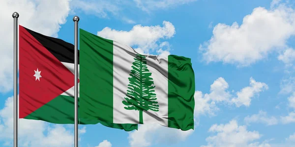 Bandera de Jordania y Norfolk Island ondeando en el viento contra el cielo azul nublado blanco juntos. Concepto diplomático, relaciones internacionales . — Foto de Stock