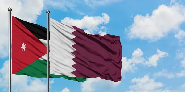 Bandera de Jordania y Qatar ondeando en el viento contra el cielo azul nublado blanco juntos. Concepto diplomático, relaciones internacionales . — Foto de Stock