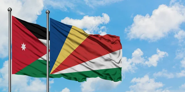Bandera de Jordania y Seychelles ondeando en el viento contra el cielo azul nublado blanco juntos. Concepto diplomático, relaciones internacionales . — Foto de Stock