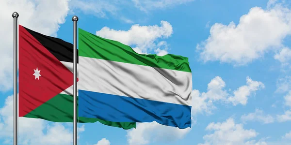 Bandera de Jordania y Sierra Leona ondeando en el viento contra el cielo azul nublado blanco juntos. Concepto diplomático, relaciones internacionales . — Foto de Stock