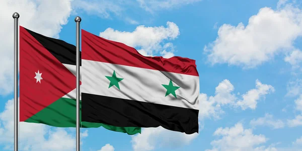 Bandera de Jordania y Siria ondeando en el viento contra el cielo azul nublado blanco juntos. Concepto diplomático, relaciones internacionales . — Foto de Stock