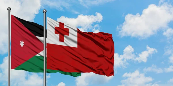 Bandera de Jordania y Tonga ondeando en el viento contra el cielo azul nublado blanco juntos. Concepto diplomático, relaciones internacionales . — Foto de Stock