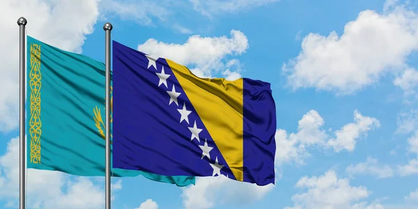 Bandera de Kazajstán y Bosnia Herzegovina ondeando en el viento contra el cielo azul nublado blanco juntos. Concepto diplomático, relaciones internacionales . — Foto de Stock