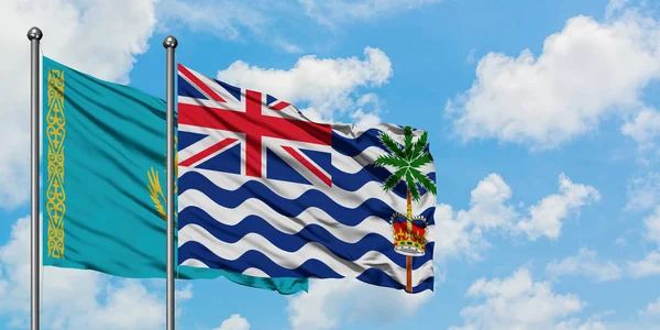 Bandera de Kazajstán y del Territorio Británico del Océano Índico ondeando en el viento contra el cielo azul nublado blanco juntos. Concepto diplomático, relaciones internacionales . — Foto de Stock