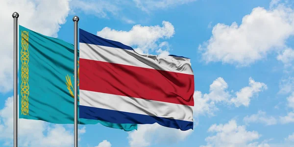 Bandera de Kazajstán y Costa Rica ondeando en el viento contra el cielo azul nublado blanco juntos. Concepto diplomático, relaciones internacionales . — Foto de Stock