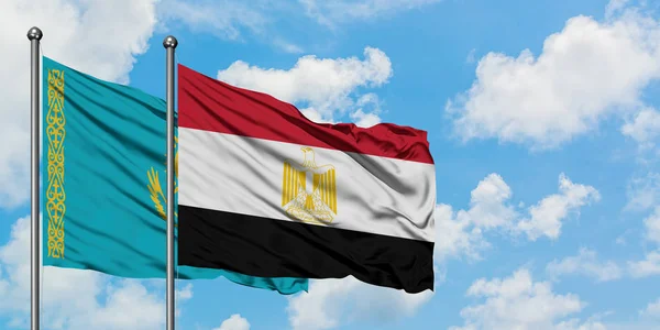 Bandera de Kazajstán y Egipto ondeando en el viento contra el cielo azul nublado blanco juntos. Concepto diplomático, relaciones internacionales . — Foto de Stock