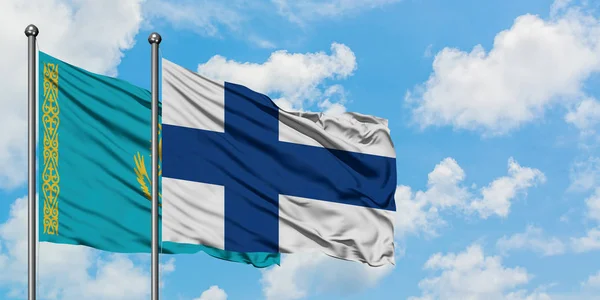 Kazakistan e Finlandia bandiera sventolando nel vento contro bianco cielo blu nuvoloso insieme. Concetto di diplomazia, relazioni internazionali . — Foto Stock