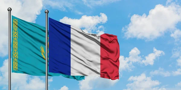 Bandera de Kazajstán y Francia ondeando en el viento contra el cielo azul nublado blanco juntos. Concepto diplomático, relaciones internacionales . — Foto de Stock