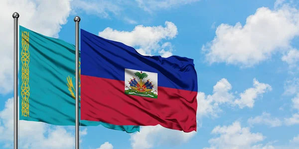 Bandera de Kazajstán y Haití ondeando en el viento contra el cielo azul nublado blanco juntos. Concepto diplomático, relaciones internacionales . — Foto de Stock