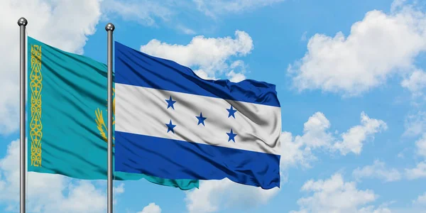 Kazakistan e Honduras bandiera sventolando nel vento contro bianco cielo blu nuvoloso insieme. Concetto di diplomazia, relazioni internazionali . — Foto Stock
