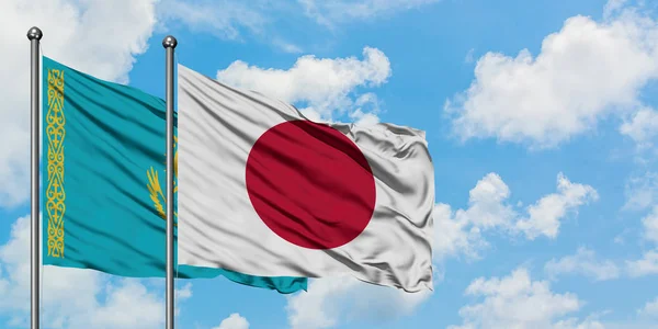 Bendera Kazakhstan dan Jepang melambai dalam angin melawan langit biru putih bersama-sama. Konsep diplomasi, hubungan internasional . — Stok Foto