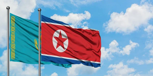 Η σημαία του Καζακστάν και της Βόρειας Κορέας κουνώντας τον άνεμο ενάντια στον λευκό θολό γαλάζιο ουρανό μαζί. Φιλοσοφία της διπλωματίας, διεθνείς σχέσεις. — Φωτογραφία Αρχείου