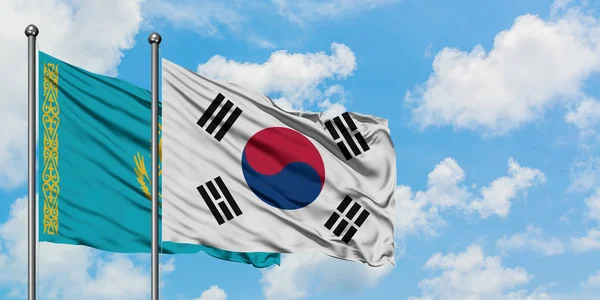 Kazakistan ve Güney Kore bayrağı birlikte beyaz bulutlu mavi gökyüzüne karşı rüzgarsal sallayarak. Diplomasi kavramı, uluslararası ilişkiler. — Stok fotoğraf