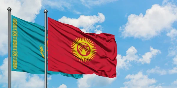 Bandera de Kazajstán y Kirguistán ondeando en el viento contra el cielo azul nublado blanco juntos. Concepto diplomático, relaciones internacionales . — Foto de Stock