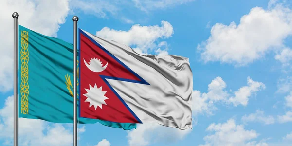 Bandera de Kazajstán y Nepal ondeando en el viento contra el cielo azul nublado blanco juntos. Concepto diplomático, relaciones internacionales . — Foto de Stock