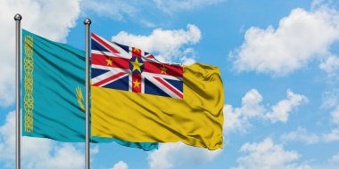 Kazakistan ve Niue bayrağı birlikte beyaz bulutlu mavi gökyüzüne karşı rüzgarda sallayarak. Diplomasi kavramı, uluslararası ilişkiler.