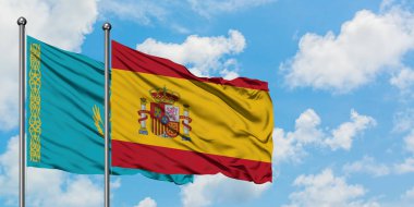 Kazakistan ve İspanya bayrağı birlikte beyaz bulutlu mavi gökyüzüne karşı rüzgarsal sallayarak. Diplomasi kavramı, uluslararası ilişkiler.