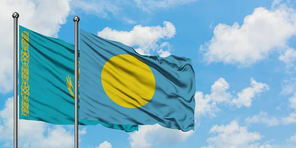 Bandera de Kazajstán y Palaos ondeando en el viento contra el cielo azul nublado blanco juntos. Concepto diplomático, relaciones internacionales . — Foto de Stock