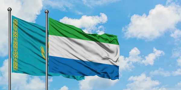 Bandera de Kazajstán y Sierra Leona ondeando en el viento contra el cielo azul nublado blanco juntos. Concepto diplomático, relaciones internacionales . — Foto de Stock