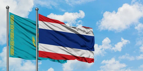 Kasachstan und die thailändische Flagge wehen gemeinsam im Wind vor dem wolkenverhangenen blauen Himmel. Diplomatie-Konzept, internationale Beziehungen. — Stockfoto