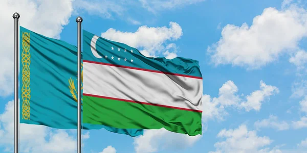 Bandera de Kazajstán y Uzbekistán ondeando en el viento contra el cielo azul nublado blanco juntos. Concepto diplomático, relaciones internacionales . —  Fotos de Stock