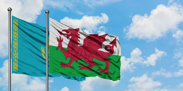 カザフスタンとウェールズの旗は、一緒に白い曇り青い空に対して風に手を振る。外交概念、国際関係. — ストック写真