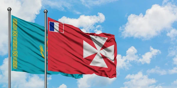 Kazajstán y Wallis y la bandera de Futuna ondeando en el viento contra el cielo azul nublado blanco juntos. Concepto diplomático, relaciones internacionales . — Foto de Stock