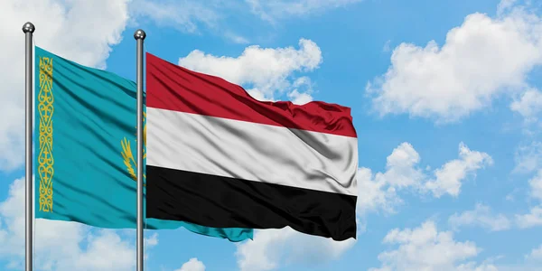 Bandera de Kazajstán y Yemen ondeando en el viento contra el cielo azul nublado blanco juntos. Concepto diplomático, relaciones internacionales . — Foto de Stock