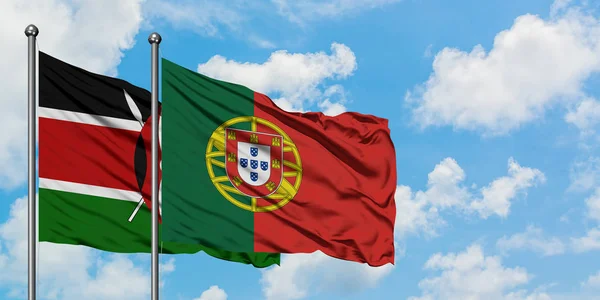 Флаг Кении и Португалии, размахивающий на ветру против белого облачного голубого неба. Концепция дипломатии, международные отношения . — стоковое фото