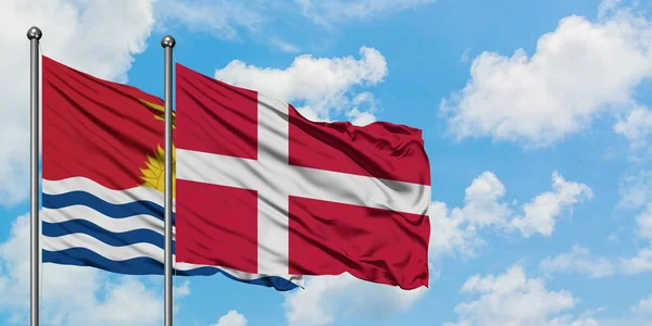 Kiribati e a bandeira da Dinamarca agitando no vento contra o céu azul nublado branco juntos. Conceito de diplomacia, relações internacionais . — Fotografia de Stock