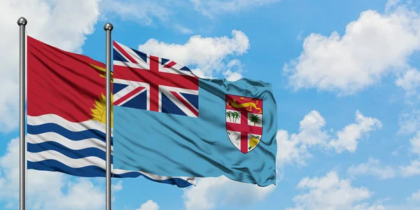 Kiribati y la bandera de Fiyi ondeando en el viento contra el cielo azul nublado blanco juntos. Concepto diplomático, relaciones internacionales . — Foto de Stock
