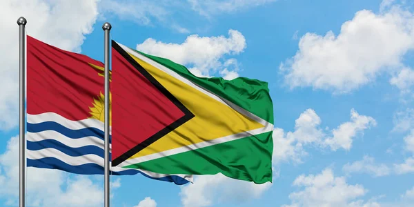 Kiribati och Guyana flagga vinka i vinden mot vit grumlig blå himmel tillsammans. Diplomatisk koncept, internationella relationer. — Stockfoto