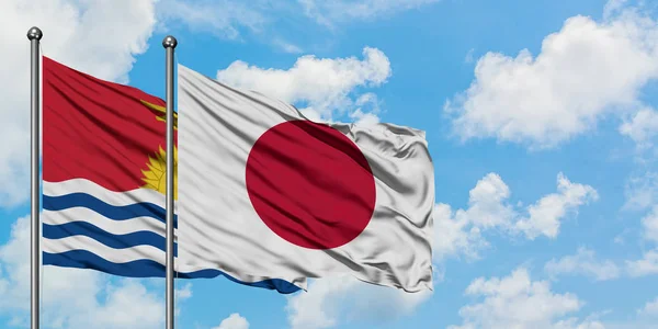 Kiribati y la bandera de Japón ondeando en el viento contra el cielo azul nublado blanco juntos. Concepto diplomático, relaciones internacionales . — Foto de Stock