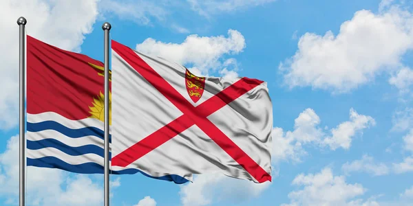 Kiribati y la bandera de Jersey ondeando en el viento contra el cielo azul nublado blanco juntos. Concepto diplomático, relaciones internacionales . — Foto de Stock