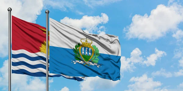 Kiribati y la bandera de San Marino ondeando en el viento contra el cielo azul nublado blanco juntos. Concepto diplomático, relaciones internacionales . — Foto de Stock