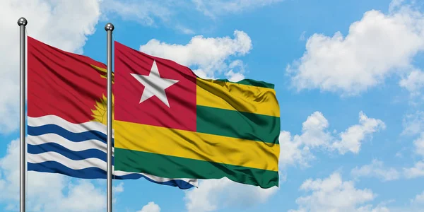 Kiribati y la bandera de Togo ondeando en el viento contra el cielo azul nublado blanco juntos. Concepto diplomático, relaciones internacionales . — Foto de Stock