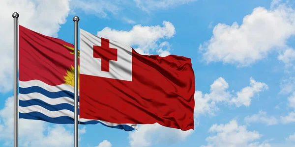 Kiribati y la bandera de Tonga ondeando en el viento contra el cielo azul nublado blanco juntos. Concepto diplomático, relaciones internacionales . — Foto de Stock