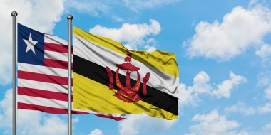 Liberya ve Brunei bayrağı birlikte beyaz bulutlu mavi gökyüzüne karşı rüzgarda sallayarak. Diplomasi kavramı, uluslararası ilişkiler.