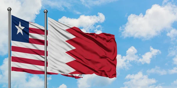 Liberia i Bahrajn flaga machając w wiatr przed białym zachmurzone błękitne niebo razem. Koncepcja dyplomacji, stosunki międzynarodowe. — Zdjęcie stockowe