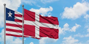 Liberya ve Danimarka bayrağı birlikte beyaz bulutlu mavi gökyüzüne karşı rüzgarda sallayarak. Diplomasi kavramı, uluslararası ilişkiler.