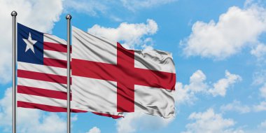 Liberya ve İngiltere bayrağı birlikte beyaz bulutlu mavi gökyüzüne karşı rüzgarda sallayarak. Diplomasi kavramı, uluslararası ilişkiler.