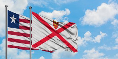 Liberya ve Jersey bayrağı birlikte beyaz bulutlu mavi gökyüzüne karşı rüzgarda sallayarak. Diplomasi kavramı, uluslararası ilişkiler.