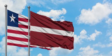 Liberya ve Letonya bayrağı birlikte beyaz bulutlu mavi gökyüzüne karşı rüzgarda sallayarak. Diplomasi kavramı, uluslararası ilişkiler.