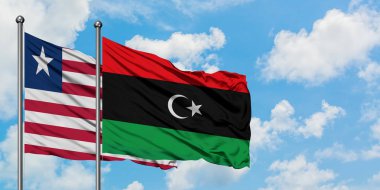 Liberya ve Libya bayrağı birlikte beyaz bulutlu mavi gökyüzüne karşı rüzgarda sallayarak. Diplomasi kavramı, uluslararası ilişkiler.