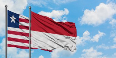 Liberya ve Monako bayrağı birlikte beyaz bulutlu mavi gökyüzüne karşı rüzgarda sallayarak. Diplomasi kavramı, uluslararası ilişkiler.