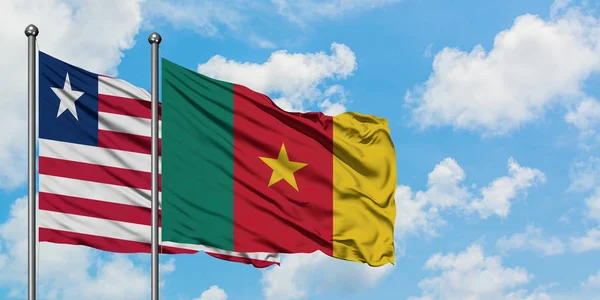 Bandera de Liberia y Camerún ondeando en el viento contra el cielo azul nublado blanco juntos. Concepto diplomático, relaciones internacionales . — Foto de Stock