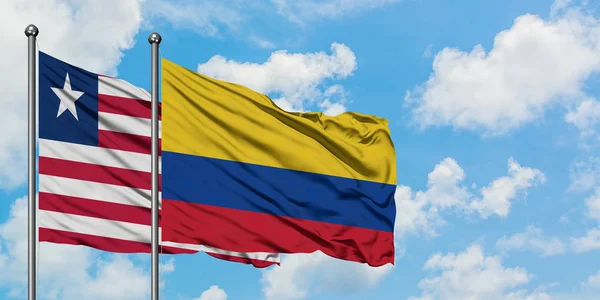 Liberia en Colombia vlag zwaaien in de wind tegen witte bewolkte blauwe hemel samen. Diplomatie concept, internationale betrekkingen. — Stockfoto