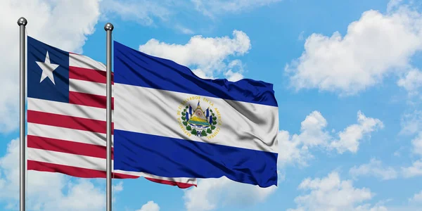 Bandera de Liberia y El Salvador ondeando en el viento contra el cielo azul nublado blanco juntos. Concepto diplomático, relaciones internacionales . — Foto de Stock