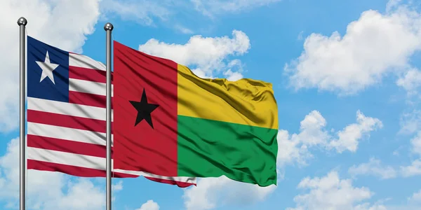 リベリアとギニアビサウの旗は、一緒に白い曇り青い空に対して風に手を振る。外交概念、国際関係. — ストック写真