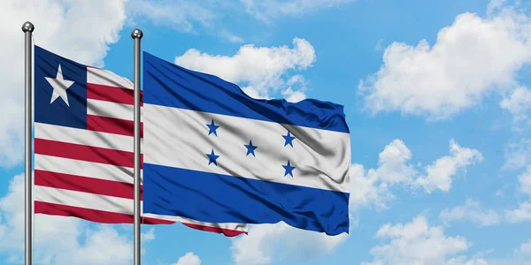 Liberia and Honduras flag waving in the wind against white cloudy blue sky together. Diplomacy concept, international relations. — Stock Photo, Image